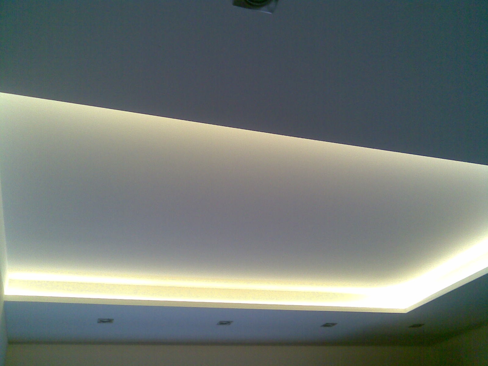 Podwieszany sufit z oświetleniem LED tworzącym efektowną, jasną obwódkę, widoczne wbudowane punkty świetlne.