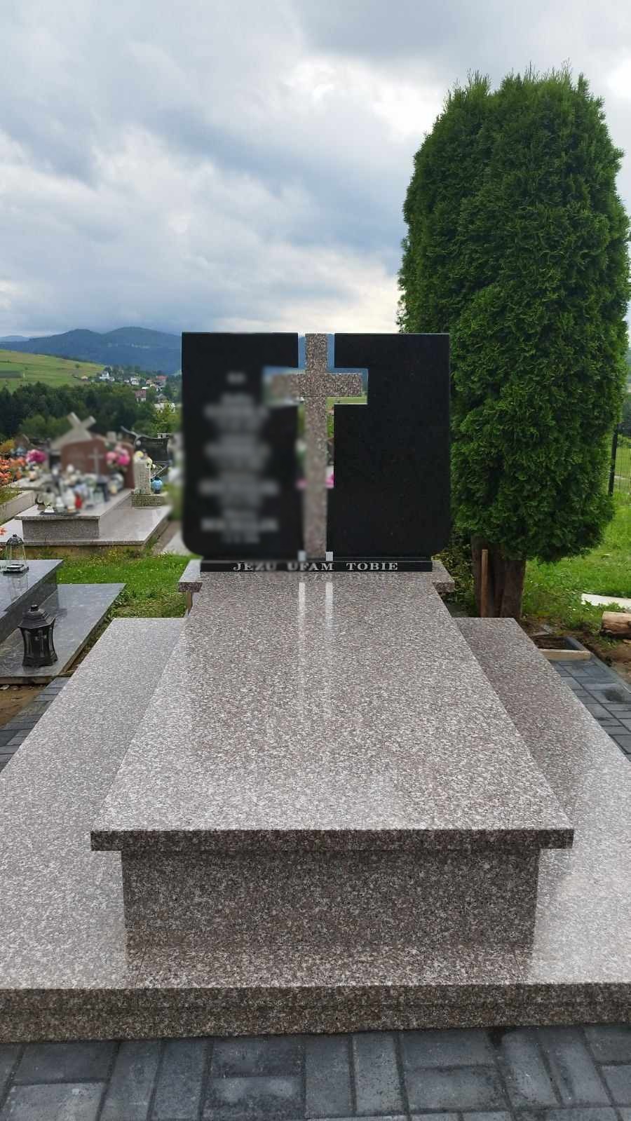 Granitowy nagrobek z czarnymi tablicami i krzyżem na tle cmentarza i gór, napis 'Jezu Ufam Tobie'.