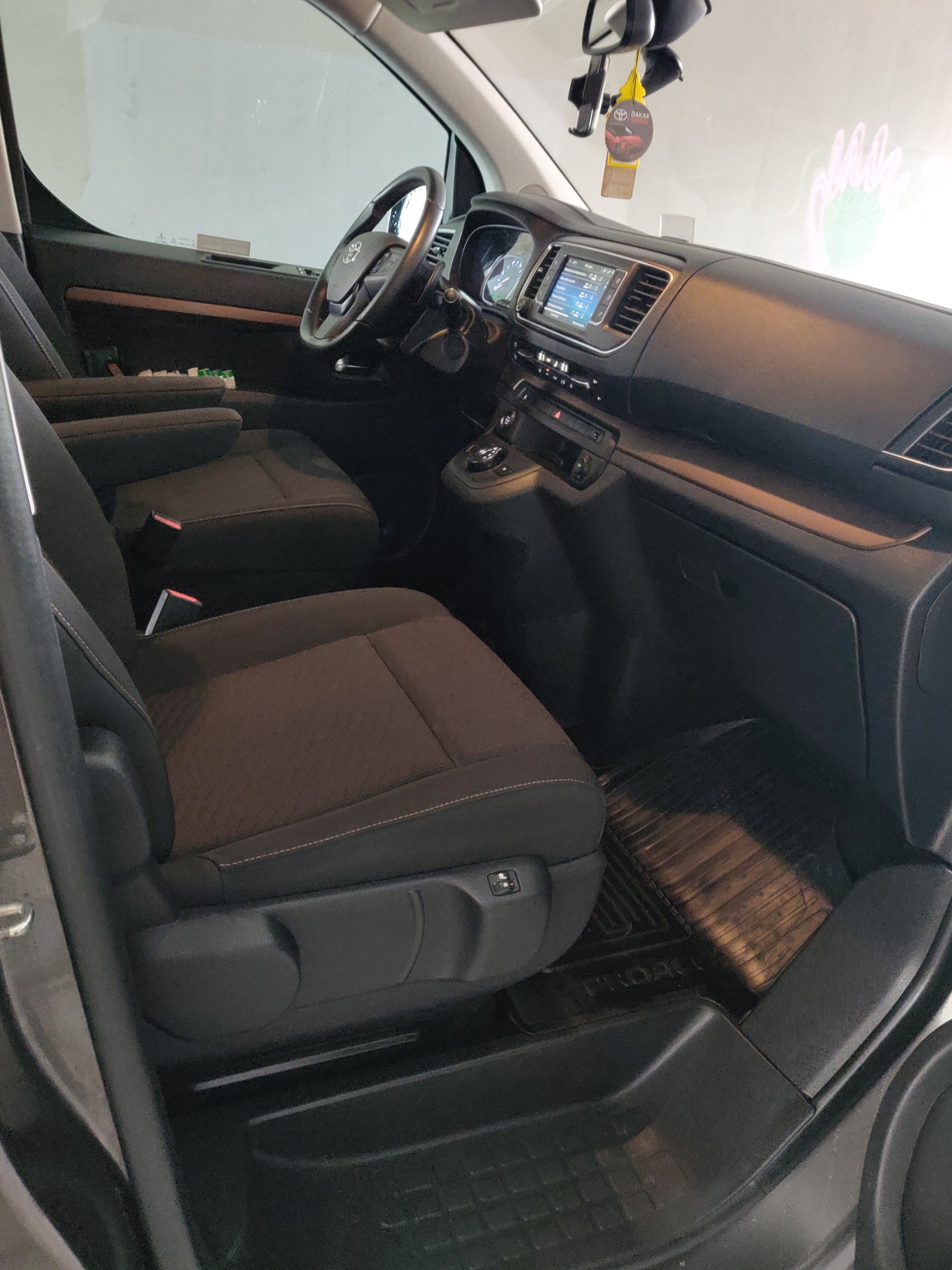 Wnętrze samochodu dostawczego z widocznymi fotelami z regulacją, deską rozdzielczą i gumowymi dywanikami podłogowymi