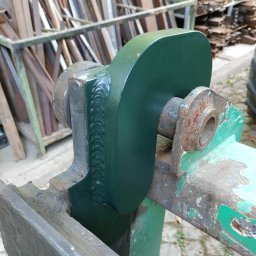 Ekoauto - Fragment konstrukcji stalowej z widocznymi spawami, pomalowanej na zielono, z elementami rdzawymi. W tle składowane profile metalowe.