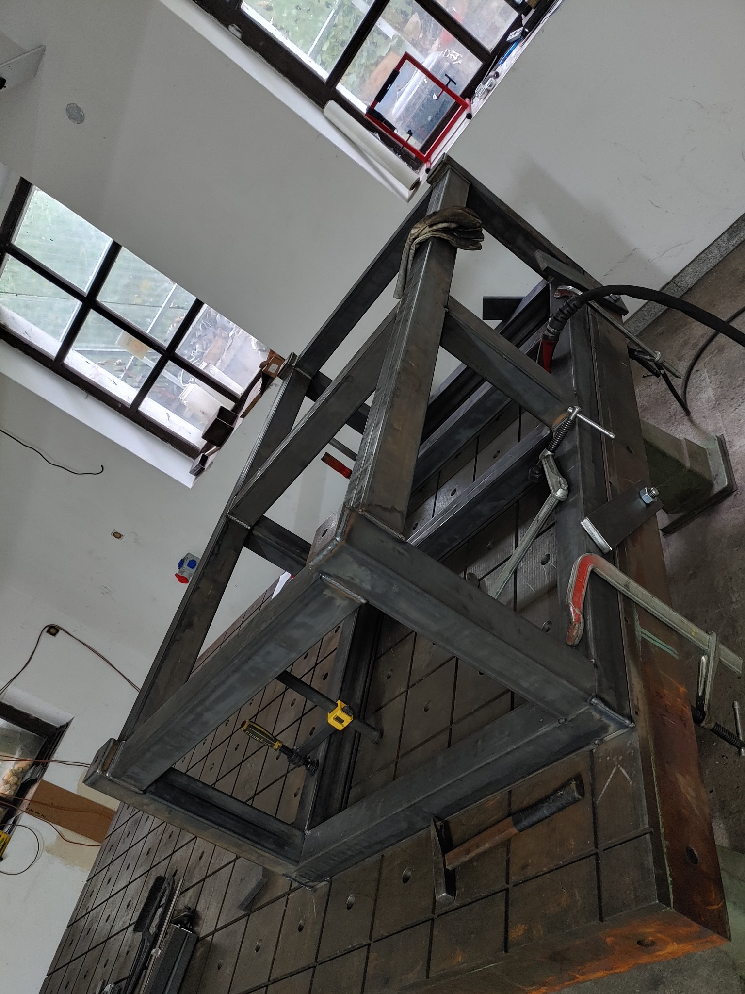 W trakcie spawania konstrukcji z profili stalowych na stole spawalniczym z widocznymi narzędziami i mocowaniami.