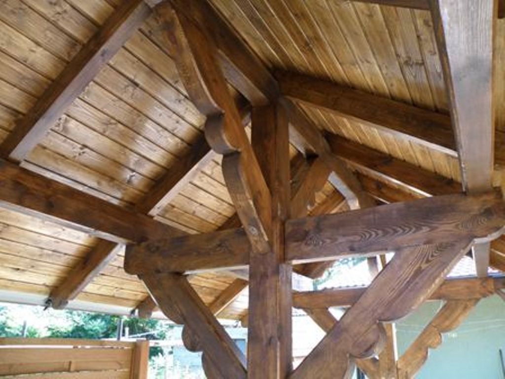 Drewniana konstrukcja dachu z belek i desek, impregnowana na ciemny brąz, widok od dołu, detale zdobione frezami.