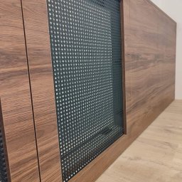 Blenda Studio meble na wymiar - Front szafy z drewnopodobnymi drzwiami i czarną, ażurową wstawką z drobnymi oczkami, widoczne na tle podłogi