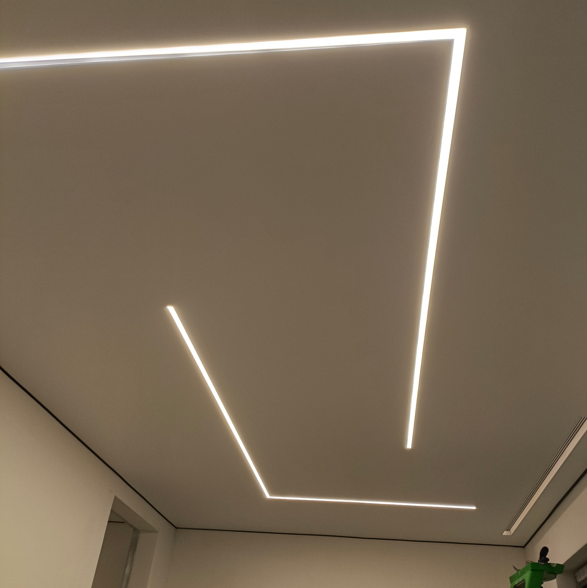 Minimalistyczny design sufitu z wbudowanym oświetleniem LED tworzącym geometryczne wzory. Nowoczesne wykończenie wnętrza z subtelnym światłem.