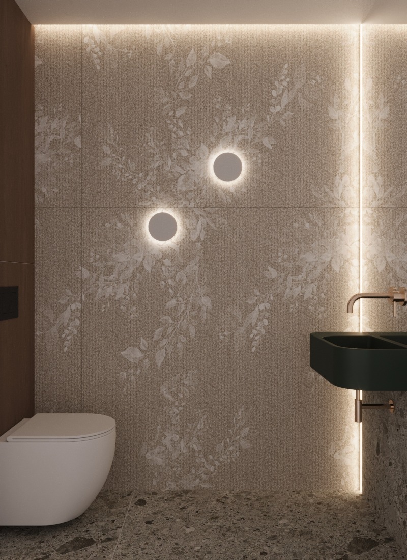 Nowoczesna łazienka z beżowymi płytkami w roślinny wzór, okrągłymi lampami ściennymi i ciemnozieloną umywalką nablatową z miedzianą armaturą.