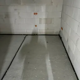 Surowy stan: kable elektryczne w peszlach prowadzone wzdłuż ściany z betonu komórkowego, puszki instalacyjne w ścianie, przewody wyprowadzone z puszek pionowo w górę.