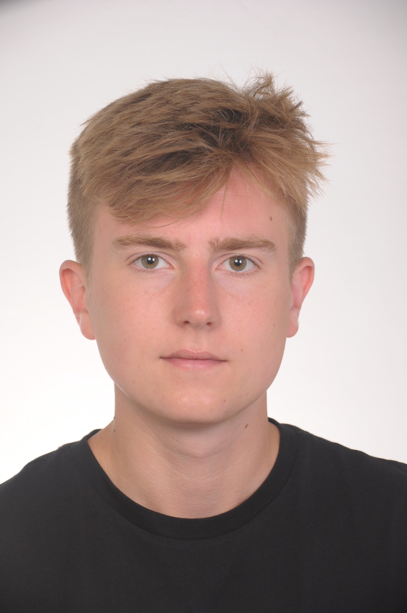 Portret młodego mężczyzny z blond włosami i czarną koszulką na białym tle.