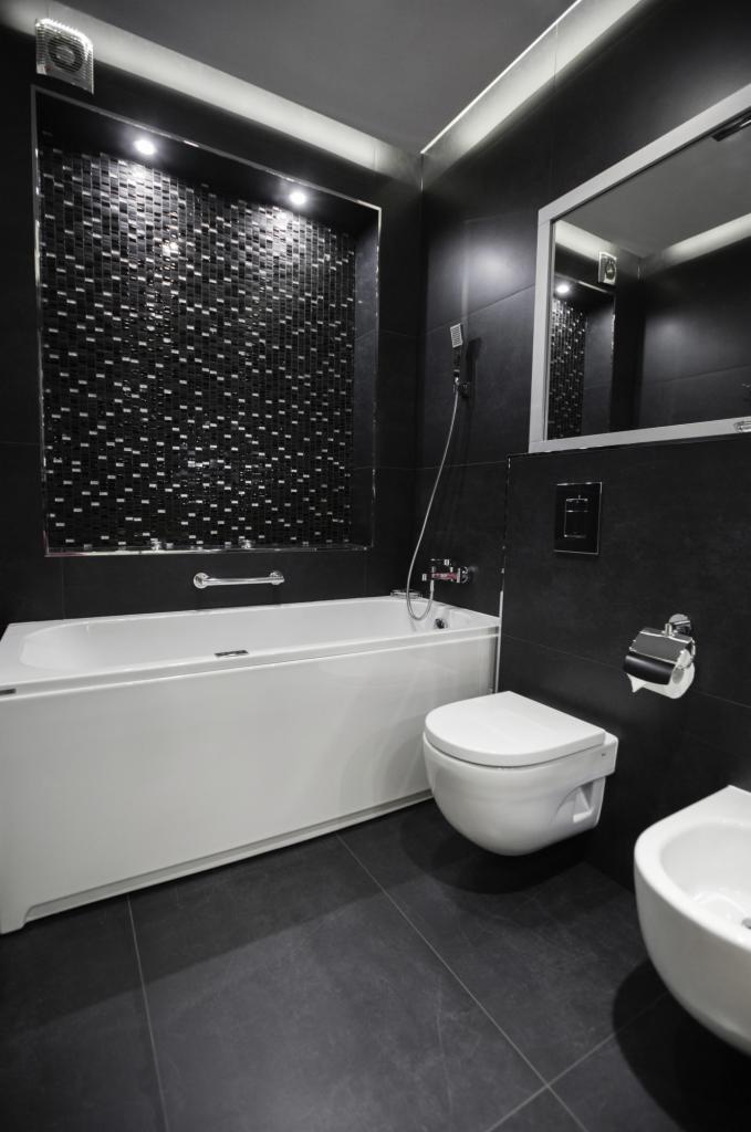 Nowoczesna łazienka w czerni i bieli z mozaiką, wanną, toaletą i bidetem, oświetleniem punktowym i dużym lustrem.