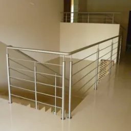 Nowoczesna, metalowa balustrada z poziomymi prętami, zamontowana na schodach i antresoli w jasnym wnętrzu.