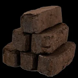 Stos sześciu prostokątnych brykietów z ciemnego, sprasowanego materiału na czarnym tle. Widoczne nierówności i tekstura brykietów.