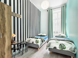 Jasny pokój dwuosobowy w hotelu SPA z łóżkami pojedynczymi, minimalistycznym wystrojem, lampką nocną na małym stoliku i dekoracyjną lampą wiszącą.