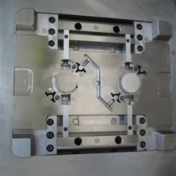 Precyzyjna, metalowa forma wtryskowa z widocznymi elementami mocującymi i kanałami wtryskowymi, umieszczona na obrotowej podstawie.