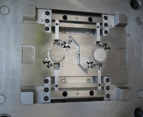 Precyzyjna, metalowa forma wtryskowa z widocznymi elementami mocującymi i kanałami wtryskowymi, umieszczona na obrotowej podstawie.