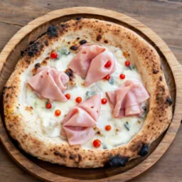 Pizza z szynką mortadella, serem pleśniowym i pomidorkami koktajlowymi na drewnianej tacy z uchwytem, z lekko przypalonym brzegiem.