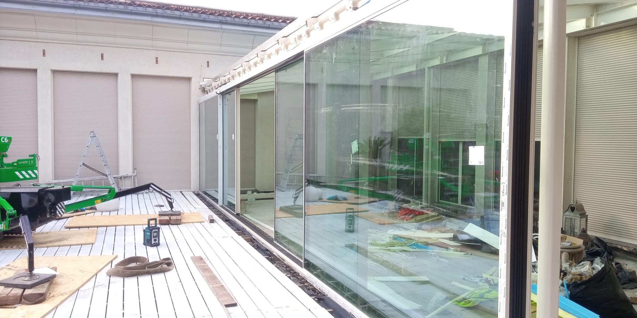 Montaż przesuwnych szklanych drzwi tarasowych, widoczny sprzęt montażowy, podnośnik próżniowy, oraz elementy konstrukcyjne w trakcie instalacji.