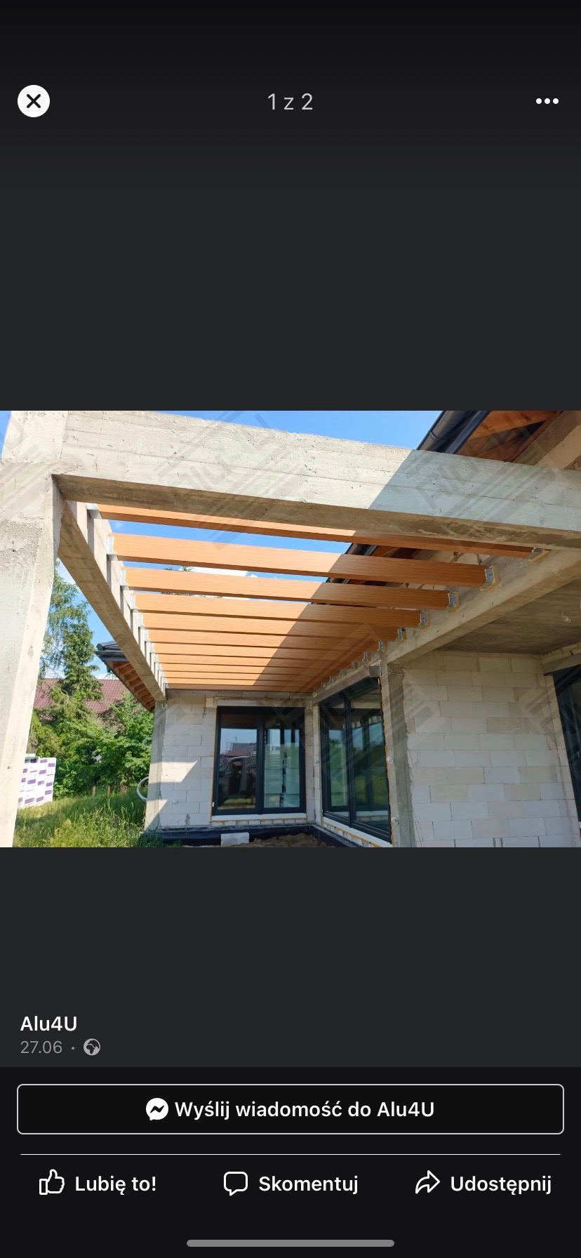 Montaż zadaszenia tarasu z drewnopodobnych paneli na metalowej konstrukcji, widoczne okna w czarnych ramach w surowym stanie budynku z białego bloczka.