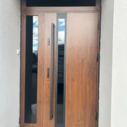 Zamontowane drzwi wejściowe Erkado Thermo Hot 88 orzech z doświetleniem bocznym i górnym. Grafitowe szyby, elektrozaczep, samozamykacz ukryty.