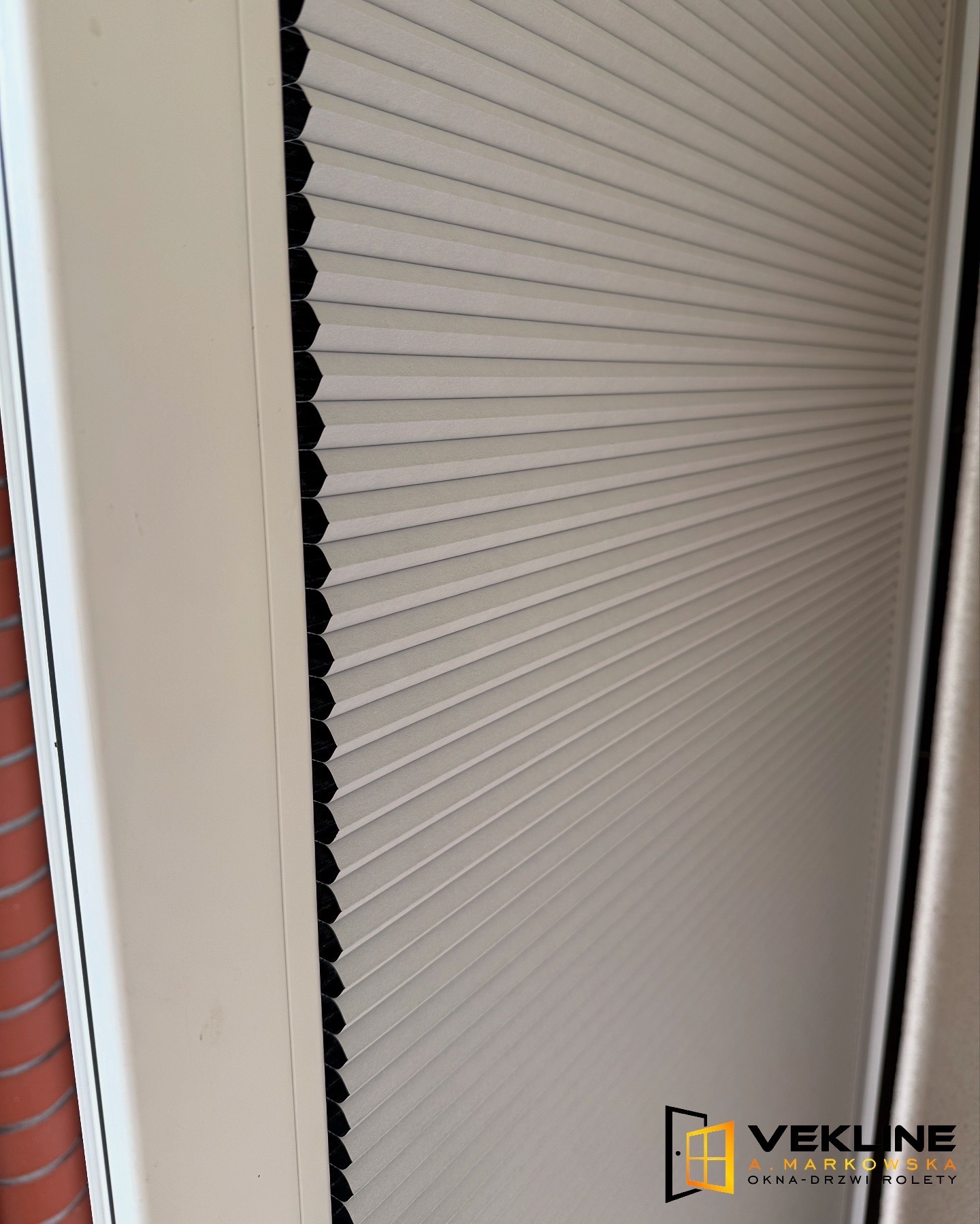 Zamknięte, termoizolacyjne plisy okienne Duo Thermo w białej ramie okiennej, z widoczną strukturą materiału i delikatnym załamaniem światła.