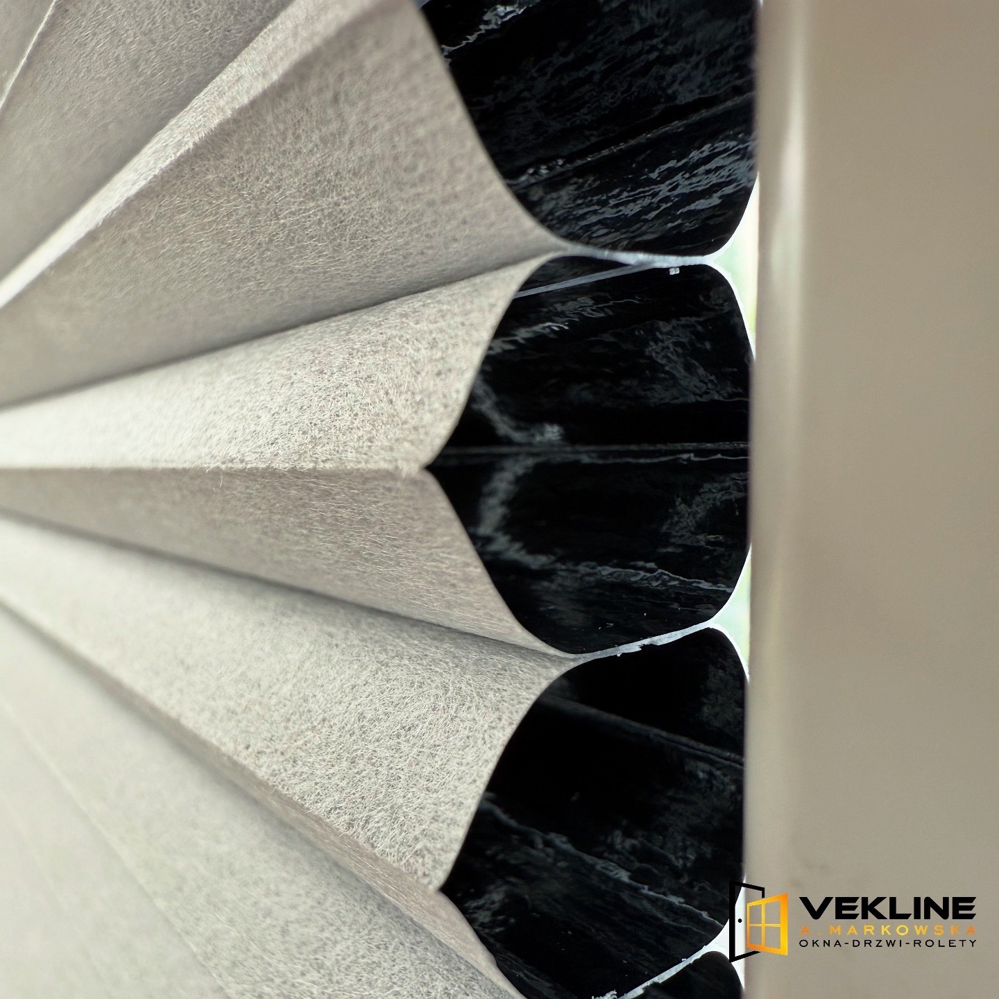 Beżowe plisy okienne w zbliżeniu, widoczne subtelne załamania materiału i delikatna faktura. Ujęcie podkreśla precyzję wykonania i elegancki wygląd.