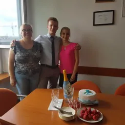 Zespół prawny świętuje sukces przy stole z tortem i truskawkami w jasnym biurze.