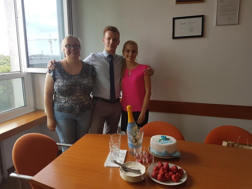 Zespół prawny świętuje sukces przy stole z tortem i truskawkami w jasnym biurze.