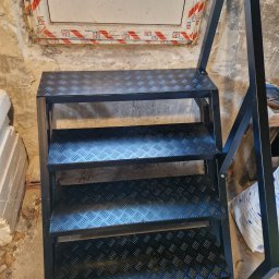 JPwelding Jakub Pawłowski - Metalowe schody z blachy ryflowanej, czarna konstrukcja, widoczne spawy, surowe wnętrze w trakcie remontu.