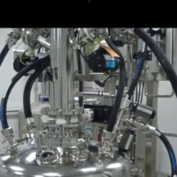 Zbliżenie na skomplikowaną instalację przemysłową ze stali nierdzewnej z licznymi rurami, zaworami i czujnikami, prawdopodobnie część większego systemu produkcyjnego.