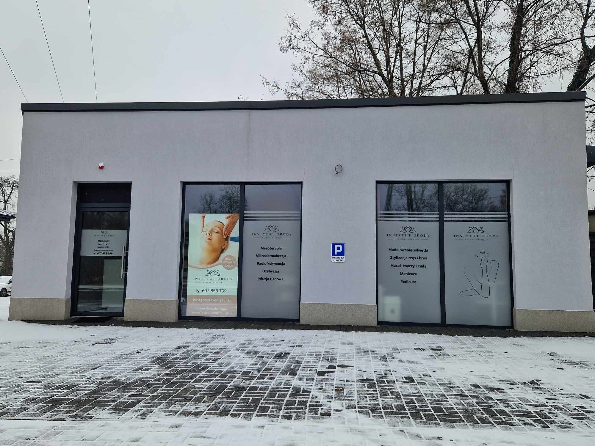 Fasada budynku Instytutu Urody z witrynami prezentującymi ofertę: mezoterapia, mikrodermabrazja, radiofrekwencja, oxybrazja, infuzja tlenowa, modelowanie sylwetki, stylizacja rzęs i brwi, masaż...