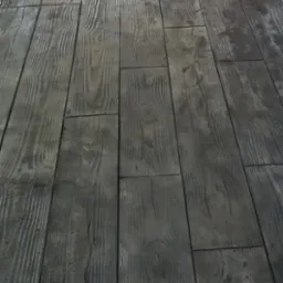 Szary betonowy chodnik z odciskiem imitującym drewniane deski, ułożony pod kątem.