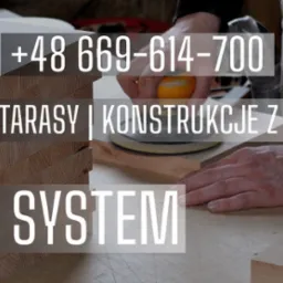 Szlifowanie drewnianego blatu za pomocą szlifierki oscylacyjnej; obok stos desek z widocznym usłojeniem.