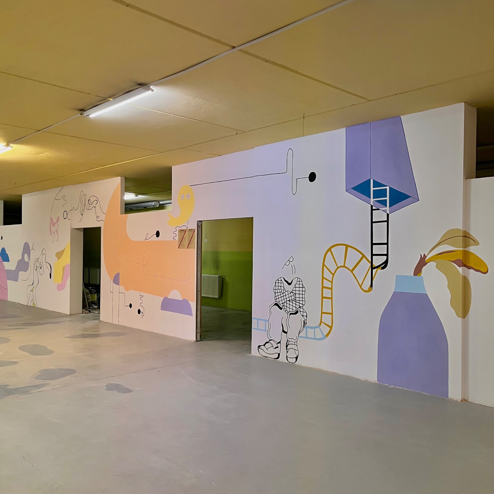 Abstrakcyjne malowidła ścienne w pastelowych kolorach zdobią wnętrze budynku, tworząc surrealistyczny i artystyczny efekt.