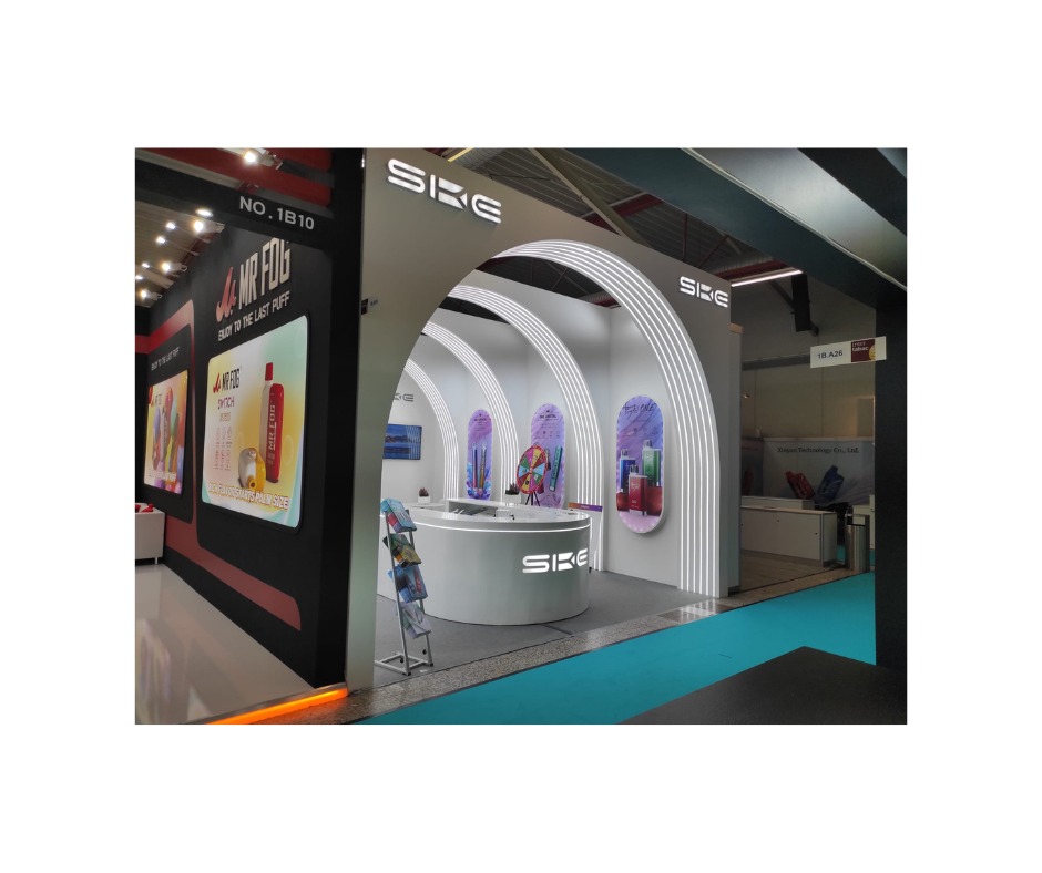 Nowoczesne stoisko targowe z białymi łukami podświetlonymi ledami, prezentujące produkty marki SKE, z ekspozycją na czarnym tle i materiałami reklamowymi na półkach.