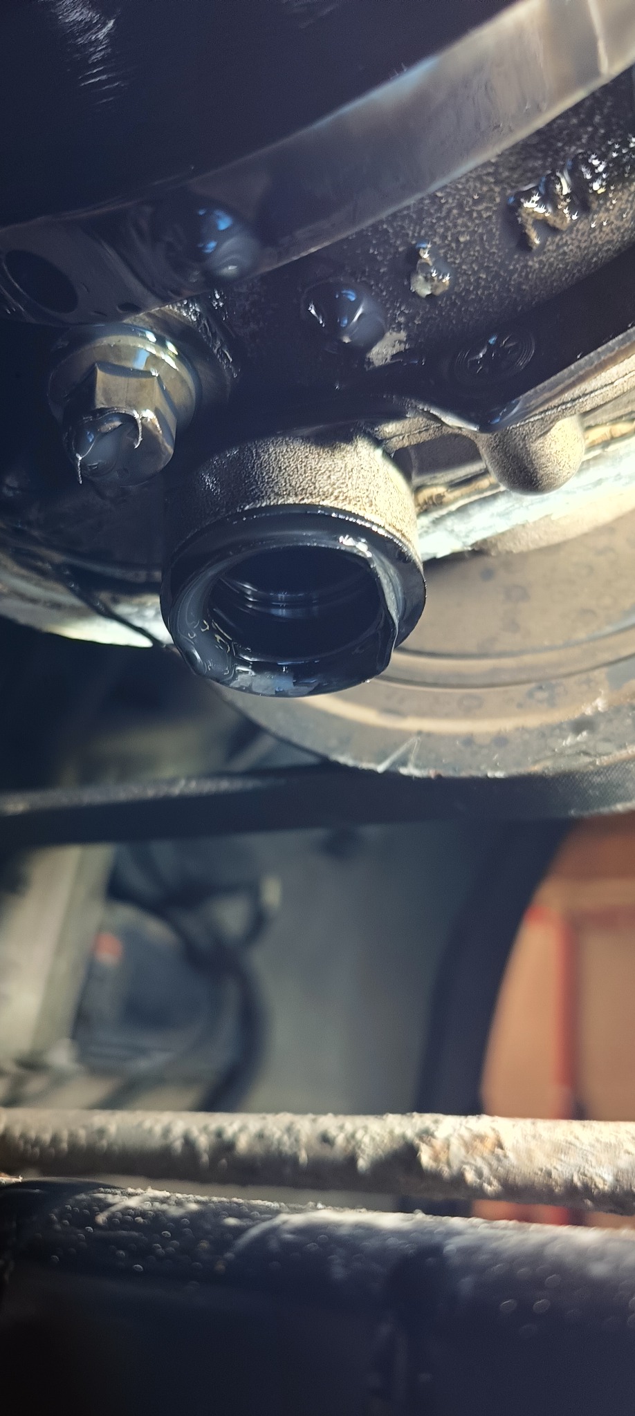 Zbliżenie na element układu smarowania silnika samochodowego z widocznymi śladami oleju.