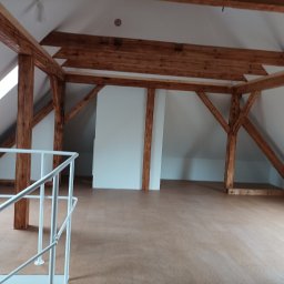 DreamBuilder - Poddasze z drewnianą konstrukcją nośną, wykończone płytami, z oknami dachowymi i białą balustradą, widoczne elementy oświetlenia.