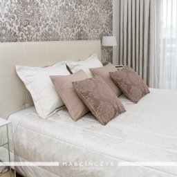 Poduszki, narzuta i zasłony w kolorach pudrowego różu i bieli do sypialni w stylu klasycznym.