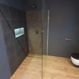 Paweł B - Nowoczesna łazienka z kabiną prysznicową typu walk-in, ciemnoszare płytki ścienne z wnęką, mozaika wewnątrz prysznica i drewnopodobna podłoga.