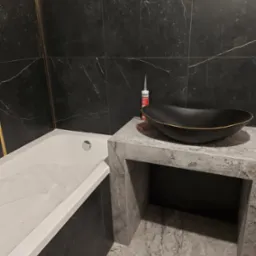 Czarna, owalna umywalka z delikatnym złotym obramowaniem na blacie z szarego marmuru, obok biała wanna z czarnymi panelami i czarne marmurowe płytki ścienne z delikatnymi złotymi akcentami...