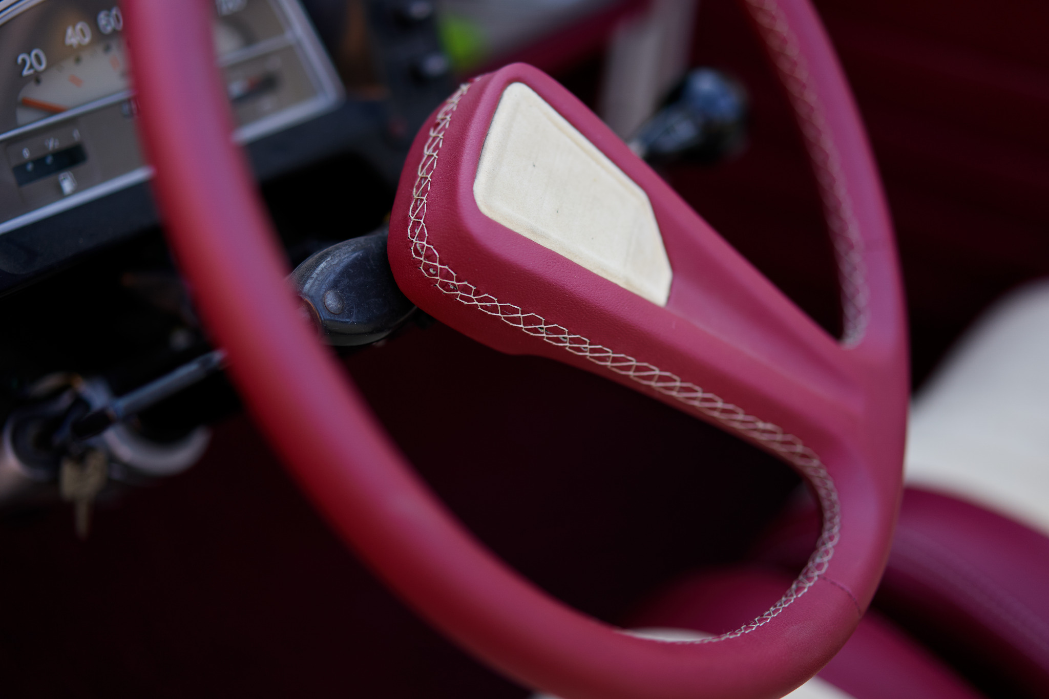 Czerwona kierownica obszyta skórą z dekoracyjnym szwem na desce rozdzielczej samochodu w Szklary.