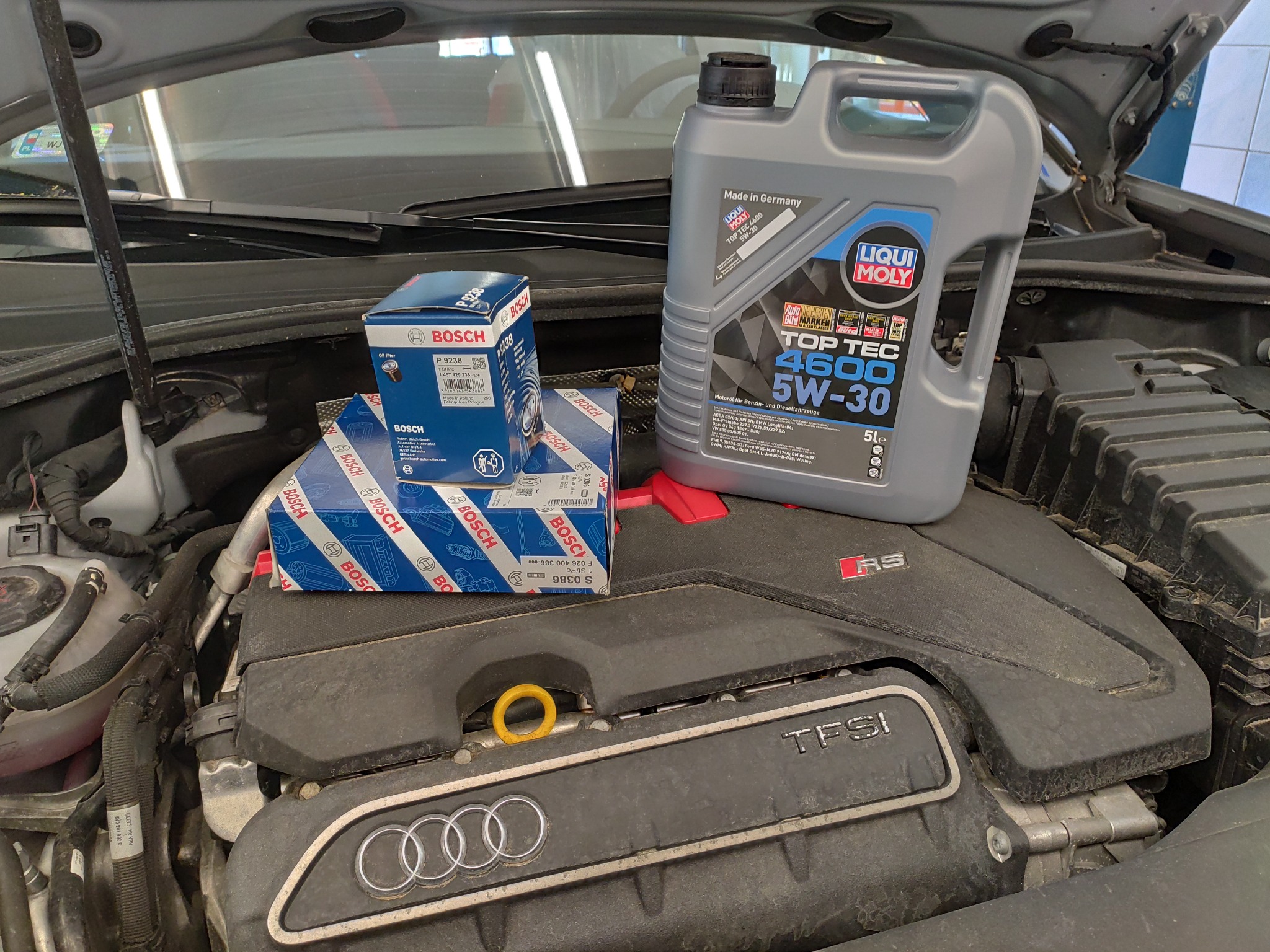 Silnik Audi z otwartą maską, widoczne pudełka filtrów oleju Bosch i kanister oleju Liqui Moly Top Tec 4600 5W-30, przygotowane do wymiany.