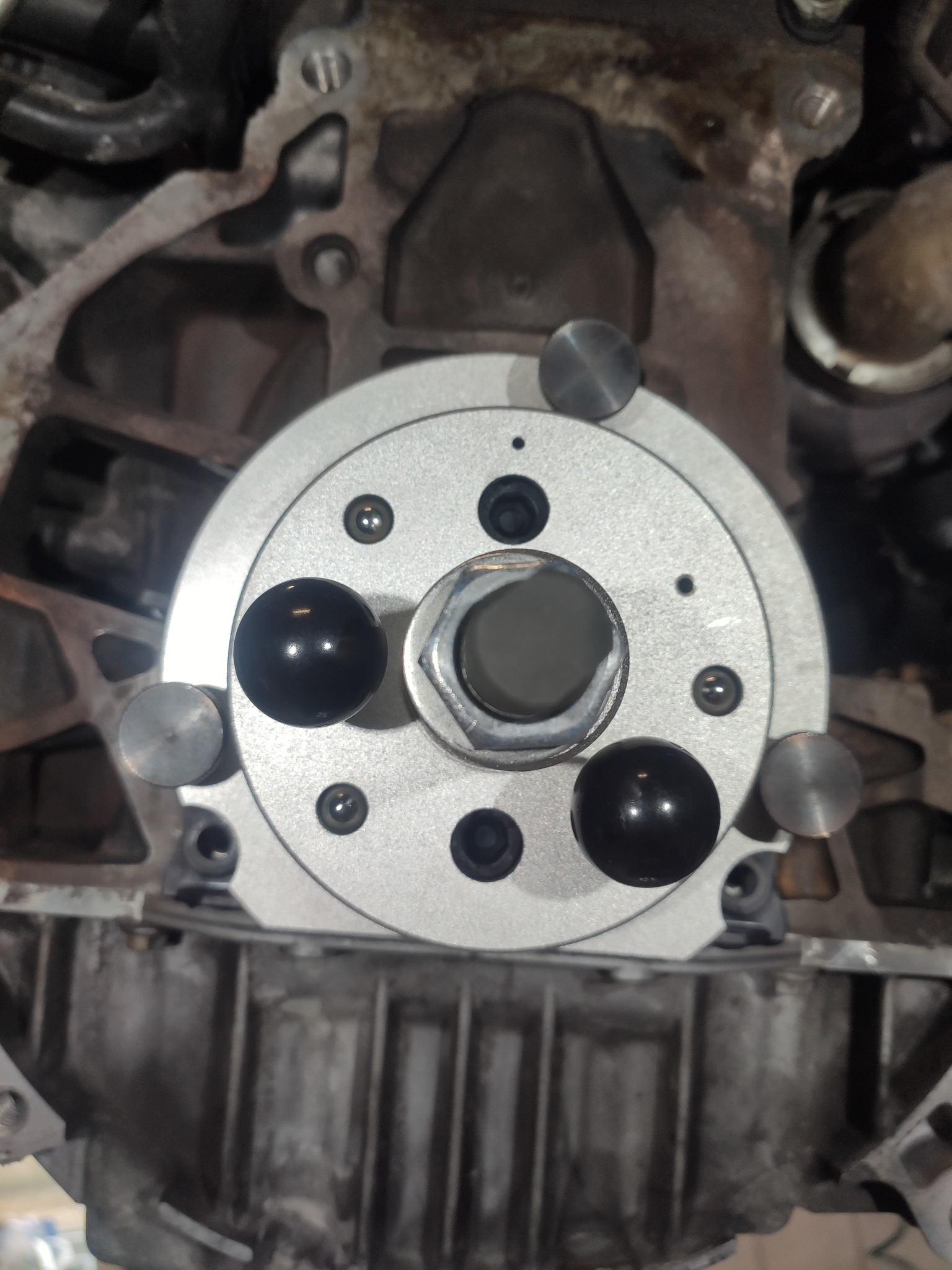 Bliski plan na blok silnika z zamontowanym narzędziem do ustawiania rozrządu w Pruszkowie, widoczne ślady użytkowania i zabrudzenia na metalowych elementach.