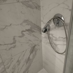 Damian Jankowski - Bateria prysznicowa z marmurową okładziną ścienną w kabinie prysznicowej.