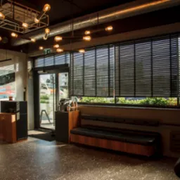 Wnętrze nowocześnie urządzonego salonu fryzjerskiego z designerską lampą, drewnianymi regałami i stanowiskiem do strzyżenia