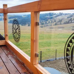 Drewniany balkon z balustradą ze szkła hartowanego z motywem regionalnym, widok na pagórkowaty krajobraz