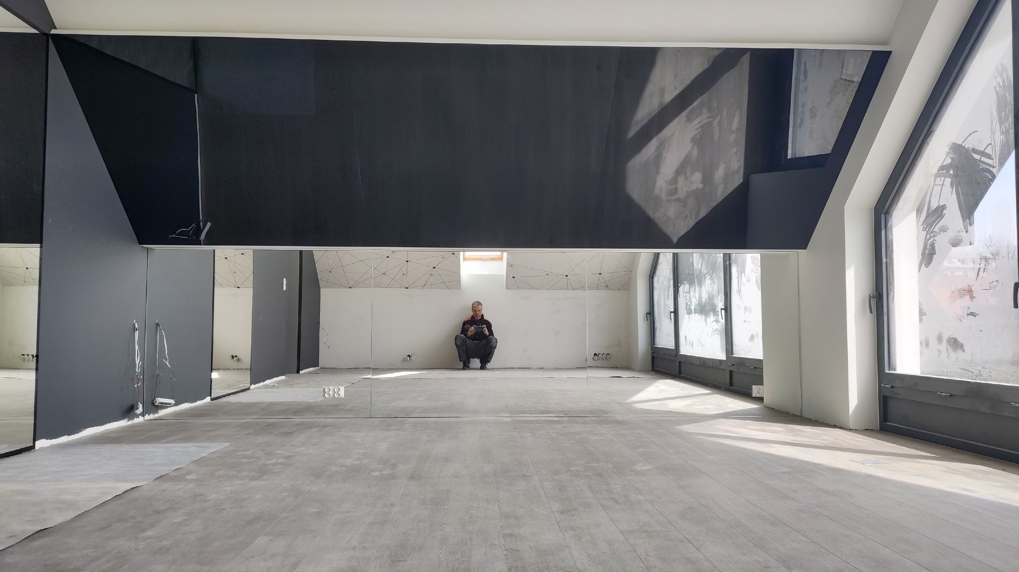 Czarny lakobel na skosach i lustra na ścianie kolankowej w siłowni