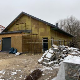 ND-BUD Nazarii Doroshchuk - Budynek w trakcie ocieplania, widoczne rusztowania, izolacja termiczna na ścianach, sterta gruzu z resztkami śniegu na pierwszym planie, pochmurne niebo.