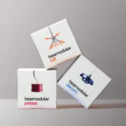 Kreatywne ułożenie trzech białych pudełek z minimalistycznymi grafikami lamp i nazwą 'beamodular' w odcieniach pomarańczy, czerwieni i błękitu na szarym tle.