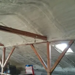 Ocieplenie poddasza pianką natryskową w Gdańsku. Widoczne drewniane elementy konstrukcyjne i równomierna warstwa izolacji termicznej na skośnym dachu.