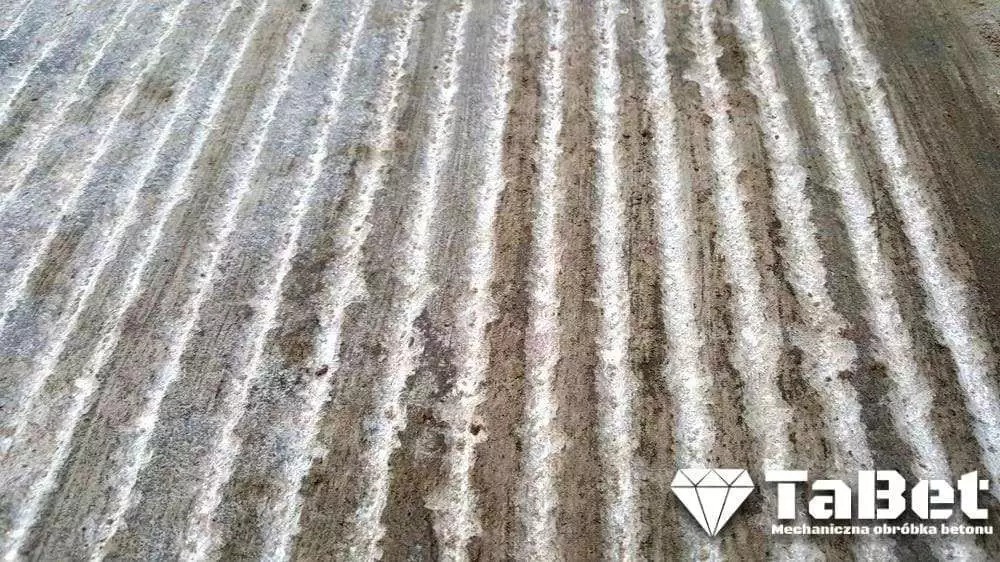 Frezowana, uszorstniona posadzka betonowa z widocznymi rowkami, zapewniająca antypoślizgowość, z logo firmy TabEt w prawym dolnym rogu.