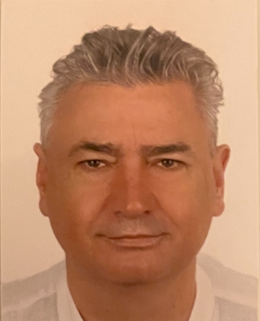 Portret mężczyzny o siwych włosach, patrzącego prosto w obiektyw z delikatnym uśmiechem.