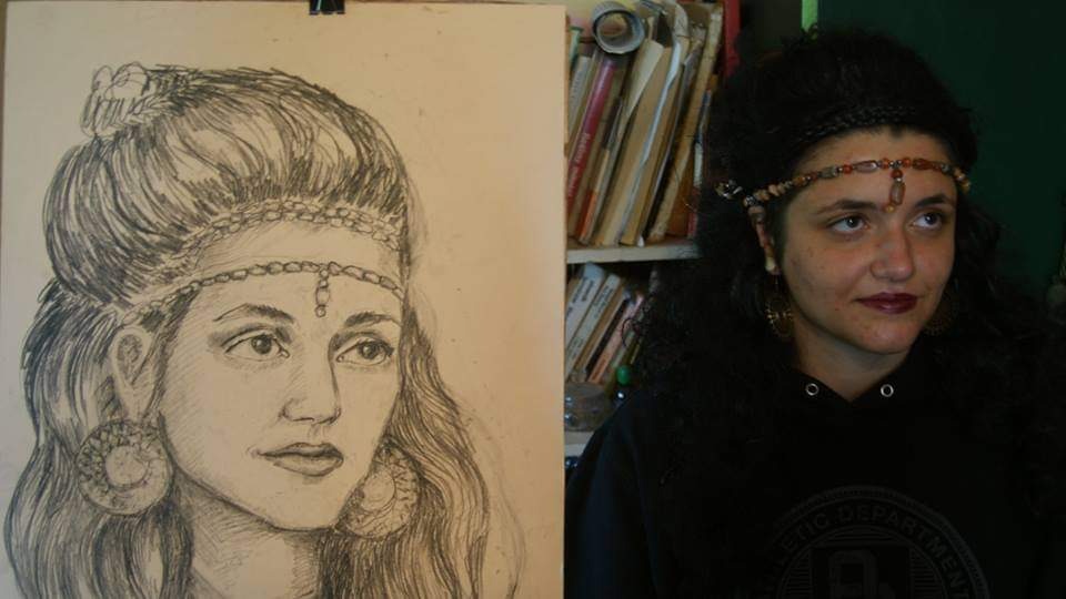 Portret szkicowany ołówkiem, przedstawiający kobietę z ozdobną opaską i kolczykami, porównany z modelką w identycznej opasce i kolczykach, pozującą obok rysunku.